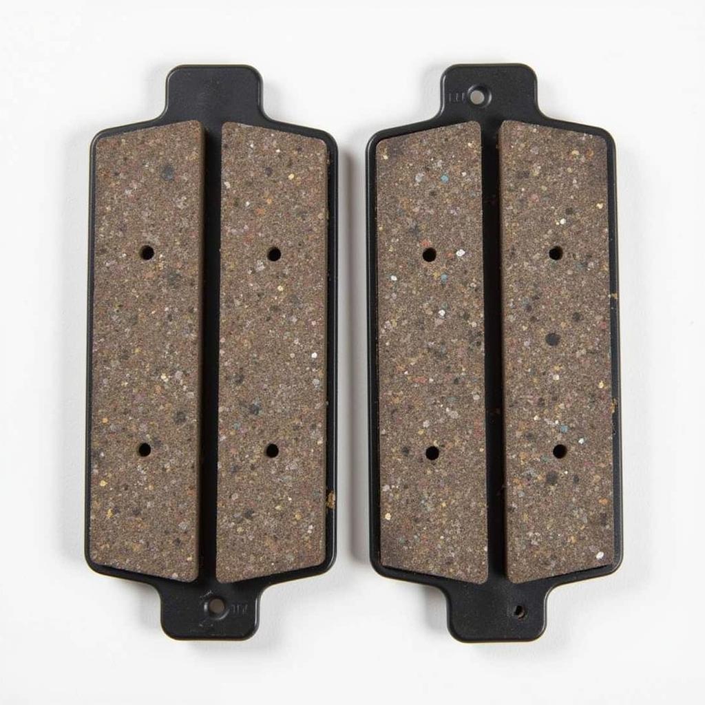 Worn Brake Pads Next to New Brake Pads